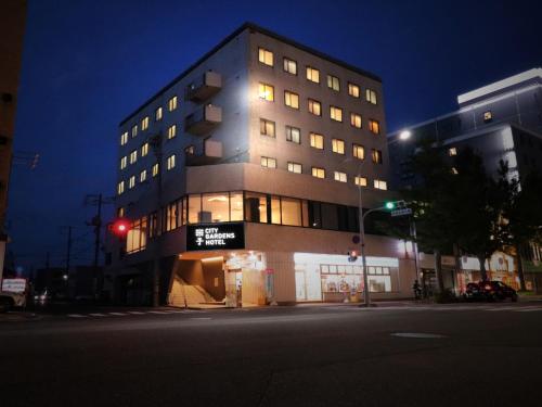 米子市米子シティガーデンズホテル Yonago Citygardens Hotel的夜幕降临的城市街道上一座高楼