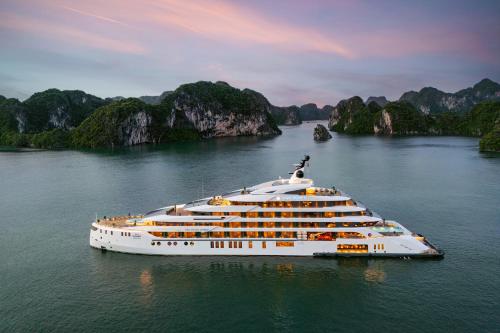 下龙湾Grand Pioneers Halong Bay Cruise 1 - former Essence Grand Halong Bay Cruise 1的一艘船在水中,背景是群山