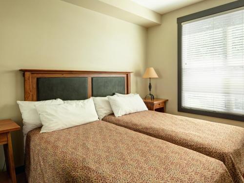 潘诺拉马Panorama Mountain Resort - Premium Condos and Townhomes的一间卧室配有带两个枕头的床和窗户