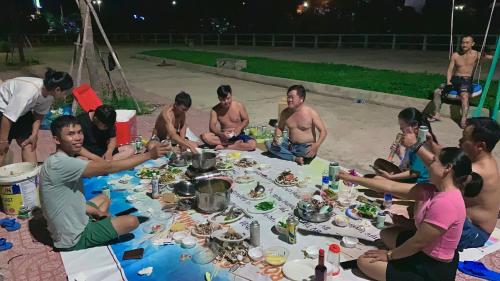 潘切Homestay Châu Triều - Phan Thiết的一群人坐在桌子旁吃着食物