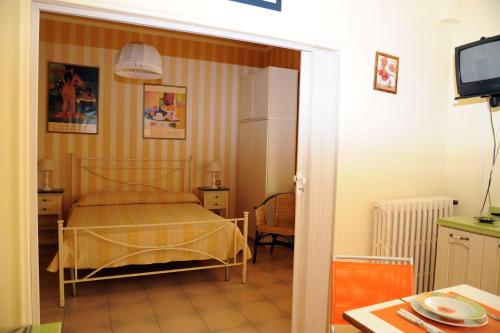 福洛尼卡Residence Il Sole的一间卧室配有一张床、一张桌子和一台电视