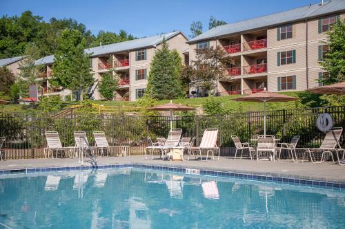 South LeeHoliday Inn Club Vacations Oak n Spruce Resort in the Berkshires an IHG Hotel的一座带椅子和遮阳伞的游泳池位于一座建筑旁边