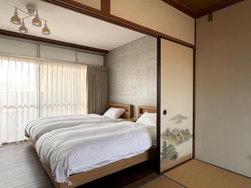 高松TRAVEL&BOOK HOTEL HULATONCABIN TAKAMATSU的一间卧室设有一张大床和一个窗户。