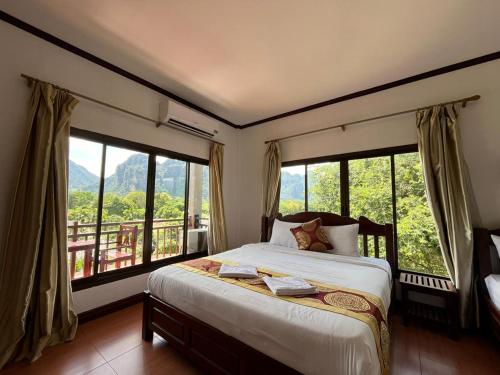 万荣Vang Vieng Hana River View Hotel & Travel的一间卧室设有一张床和大窗户