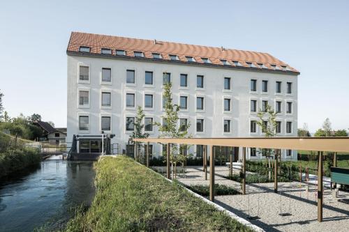 AlberswilAparthotel Luzern West的前面有一条河的白色建筑