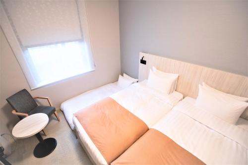 大阪Hiyori Hotel Osaka Namba Station的一间卧室设有两张床、一把椅子和一个窗户。