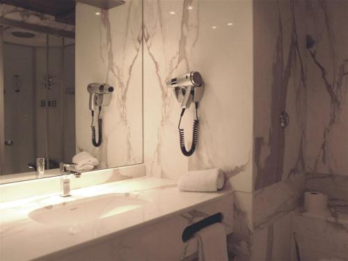 比居格利亚库尔斯酒店的一间带水槽的浴室和墙上的两部电话