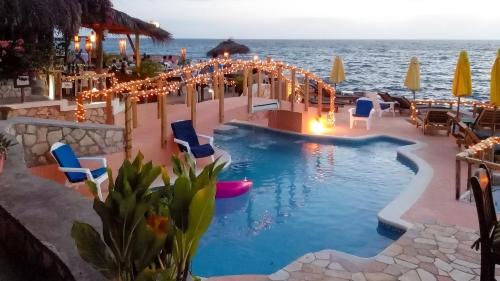 尼格瑞尔坎塔流火酒店的一个带椅子和灯的度假村游泳池