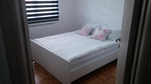 兹拉蒂博尔Apartments Milas的一张带两个粉红色枕头的白色床