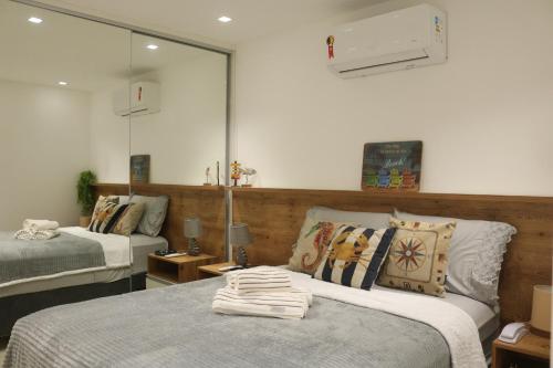 尼泰罗伊Camboinhas Loft Vista Mar, Pé na Areia, com Piscina e Churrasqueira的一间卧室配有两张床和镜子