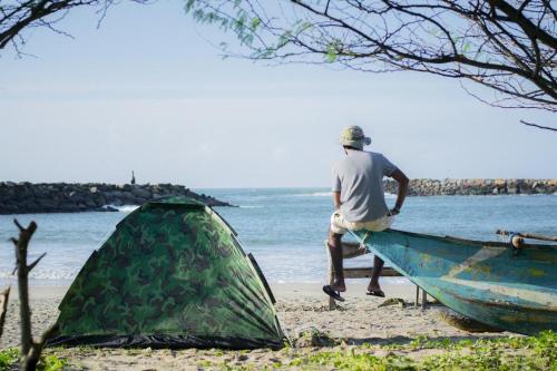 基林德Cozye Beach Camping Yala的站在海滩帐篷旁边的男人