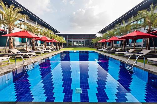 武里南武里南联阿玛瑞酒店的大楼前的游泳池配有椅子和遮阳伞