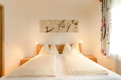 阿布特瑙Appartements Hitzenbichler的卧室配有白色的床铺和白色的枕头