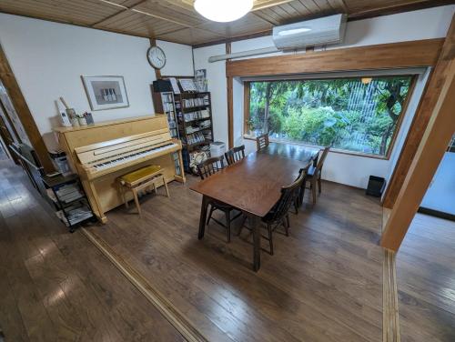 Nishioguest house Ki-zu - Vacation STAY 92940的一间带桌子和钢琴的用餐室