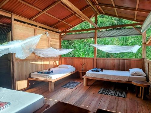 努基Lodge El Amargal - Reserva Natural, Ecoturismo & Surf的配有吊床的木制客房内的两张床