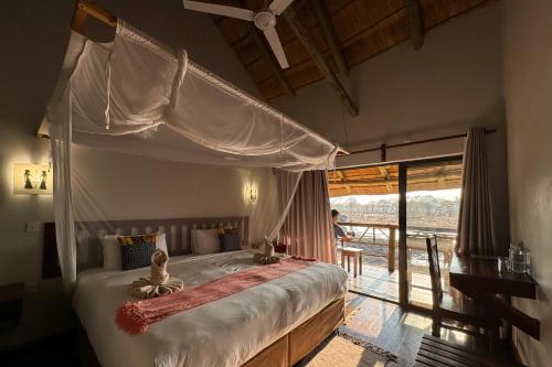 LesomaCHOBE MOPANI FOREST LODGE & CAMP SITE的一间卧室设有一张天蓬床和一个阳台