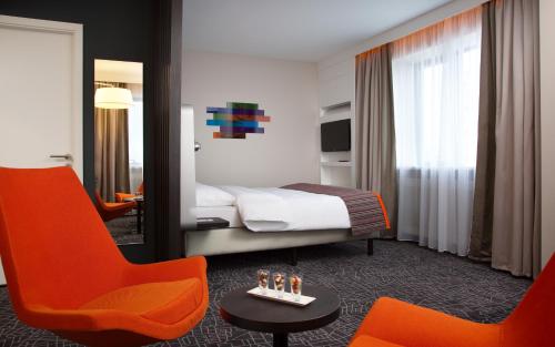 下塔吉尔Demidov Plaza的酒店客房,配有一张床和两张橙色椅子
