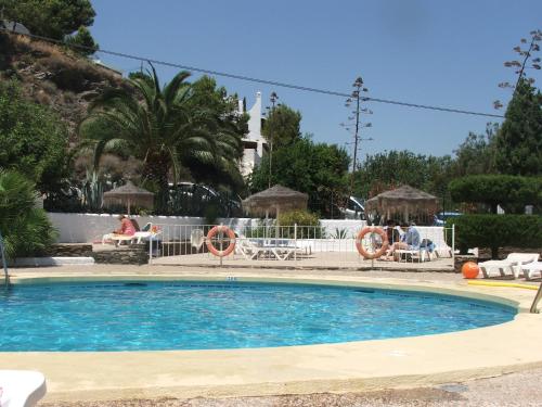 莫哈卡尔La Parata Apartments的度假村的游泳池,人们坐在椅子上