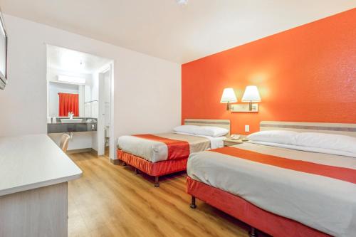 凤凰城第6凤凰城西汽车旅馆的酒店客房设有两张床和橙色的墙壁。