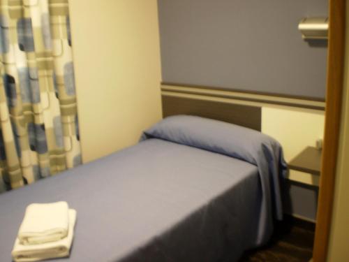 瓜达拉哈拉里卡波萨达旅馆的小房间,配有一张带蓝色毯子的床