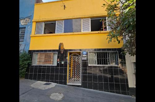 圣保罗Pinheiros Hostel & Food的黄色和黑色的房子,有门