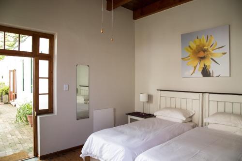 弗朗斯胡克万维克街22号观光旅馆的白色卧室内的两张床,墙上挂着鲜花