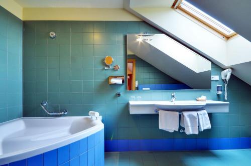 Jablonné nad Orlicí菲力品诺姆酒店的蓝色的浴室设有浴缸和水槽