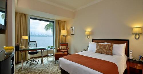 孟买海洋广场酒店的配有一张床、一张书桌和一扇窗户的酒店客房