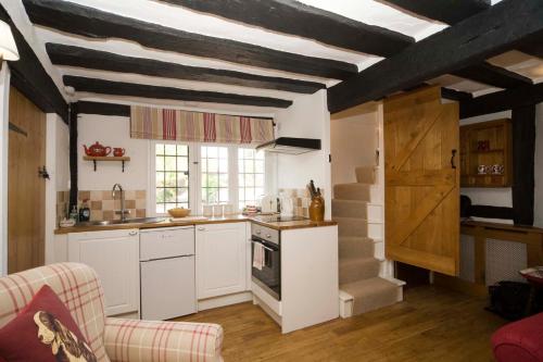 沃里克Daisy Cottage的厨房配有白色橱柜和条纹天花板