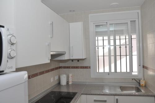阿尔科斯-德拉弗龙特拉Atiko Welcome的厨房配有白色橱柜、水槽和窗户。
