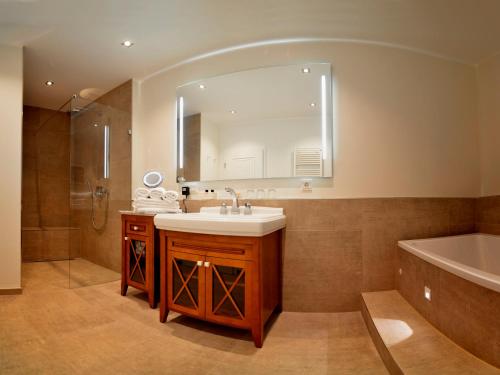 奥斯纳布吕克唯宝科尔布勒奇尔酒店餐厅及SPA的一间带水槽、浴缸和镜子的浴室