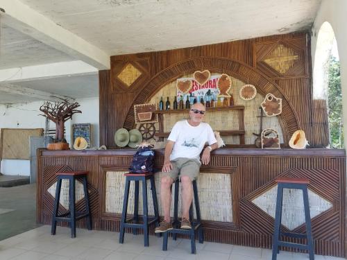 MahamboMAHAMBO BEACH hôtel的坐在酒吧前凳子上的人