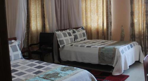 坎帕拉Pearl Highway Hotel Kibuye Kampala的一间卧室配有两张床和椅子