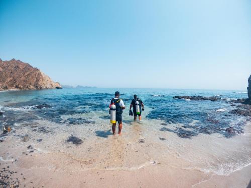 QantabQantab Village Stay的两个人在海滩上水中散步