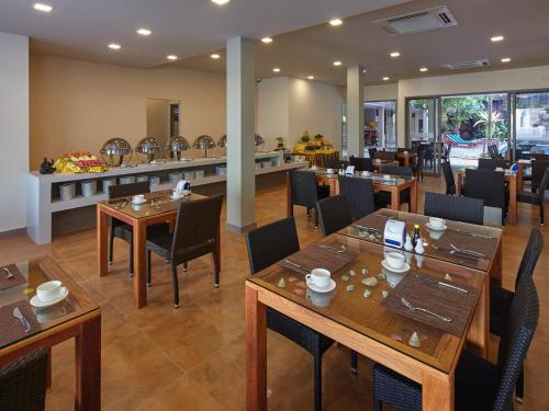 南芭堤雅芭提雅玛瑙精品度假村的餐厅设有木桌、椅子和柜台