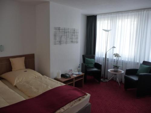 勒沃库森塞斯泽恩酒店的配有一张床和一把椅子的酒店客房