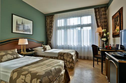 布拉格爱丽舍酒店的酒店客房设有两张床、一张书桌和一个窗户。