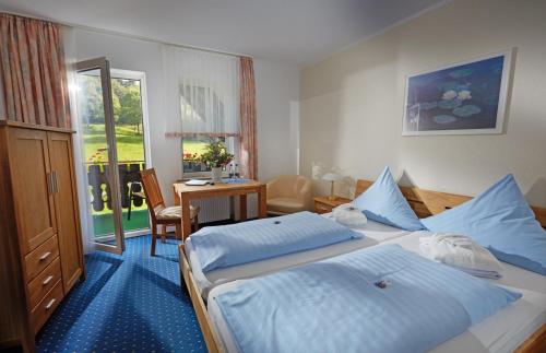 施马伦贝格汤姆斯祖尔缪旅馆的酒店客房设有两张床、一张桌子和一张书桌。