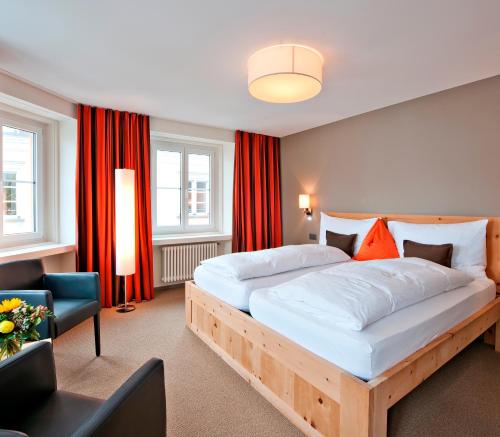 萨梅丹多纳兹酒店的一间卧室配有一张带红色窗帘的大床
