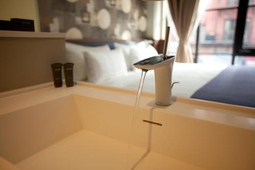 纽约诺贝尔DEN酒店的一间卧室配有一张床,柜台上配有一部电话