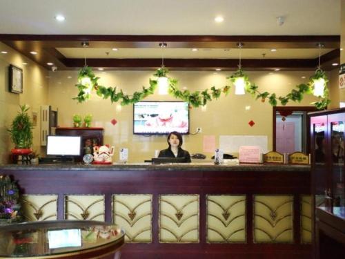 天津GreenTree Inn Tianjin Jinnan Shuanggang Lishuang Road Shell Hotel的坐在餐厅酒吧的女人