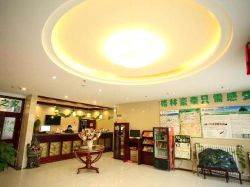 天津GreenTree Inn Tianjin Jinnan Shuanggang Lishuang Road Shell Hotel的餐厅拥有大型天花板,配有大钟