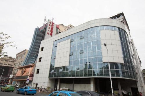 南昌Ibis Nanchang Zhongshan Road Pedestrian Street Hotel的一座大型玻璃建筑,前面有汽车停放