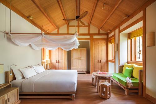 成都青城山六善酒店的卧室配有白色的床和绿色沙发