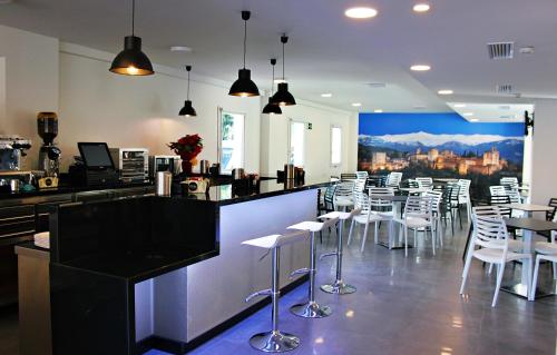 格拉纳达内瓦达城市之梦酒店的餐厅设有酒吧,配有白色的椅子和桌子