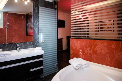 雅典马罗西酒店的带浴缸、盥洗盆和卫生间的浴室