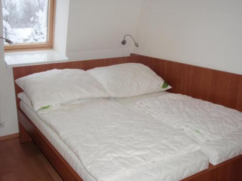 拉莫佐夫Apartmán Ramzová B14的一张带木制床头板和白色枕头的床