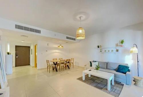 阿布扎比2BR - Al Zeina Beach Community, Al Raha Beach - 5 minutes from Zayed Int'l airport and Yas Island, F1的客厅配有蓝色的沙发和桌子