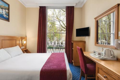 伦敦戴斯海德公园酒店的配有一张床、一张书桌和一扇窗户的酒店客房
