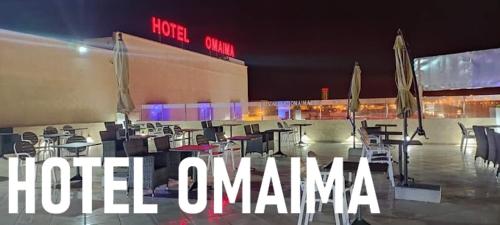 阿尤恩Hotel OMAIMA的一组桌子和椅子,位于大楼前